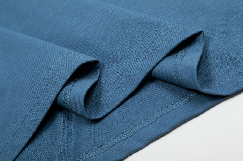 Close-up of a blue oversized T-shirt sleeve with visible hems and stitched seams on soft cotton fabric