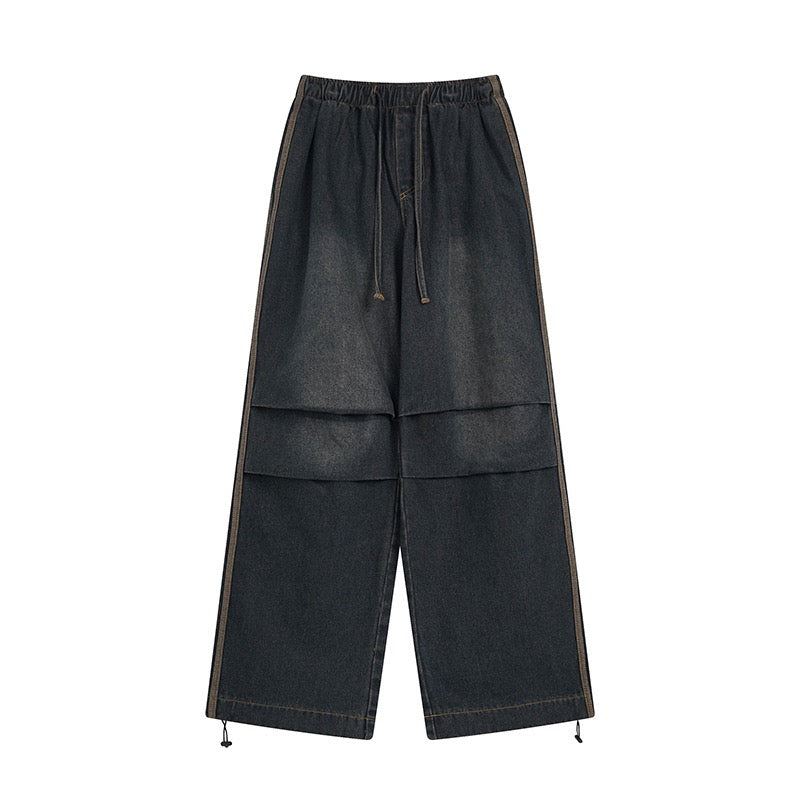 Front view of dark washed wide-leg denim pants with stacked curved front panels, contrast stitching, and drawstring elastic w