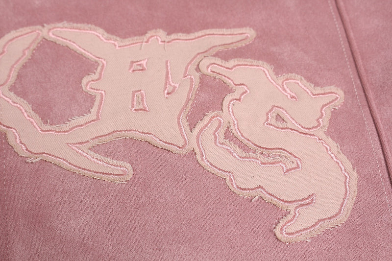 Close-up of pink hoodie logo patch with frayed edges and stitched outline