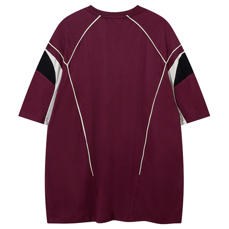 Oversized burgundy jersey tee with white seam piping and black sleeve panels, streetwear style back view