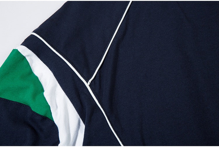Close-up of an oversized navy jersey tee with white piping and green color-block paneling on the sleeve
