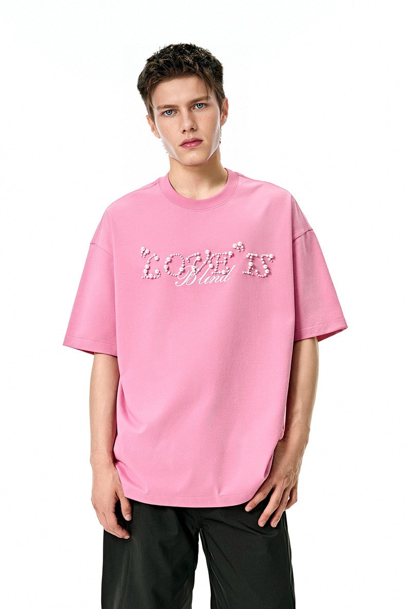 Pink oversized graphic tee with pearl rhinestone Love Is Blind script on the front, styled on a male model
