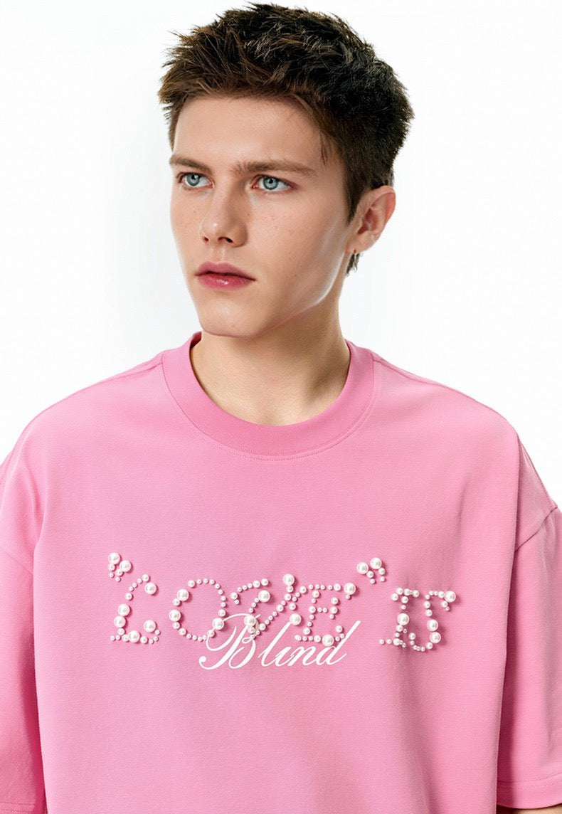 Pink streetwear tee with pearl rhinestone Love Is Blind script on the chest, worn by a male model