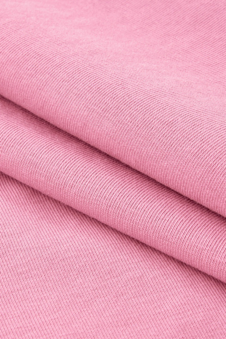Pink folded cotton tee fabric with a soft knit texture, featured for the Love Is Blind pearl rhinestone script graphic shirt