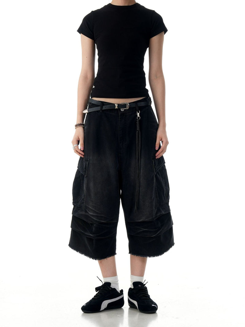 Black cargo shorts on model, front view with cropped hem, side cargo pockets, and wide legs