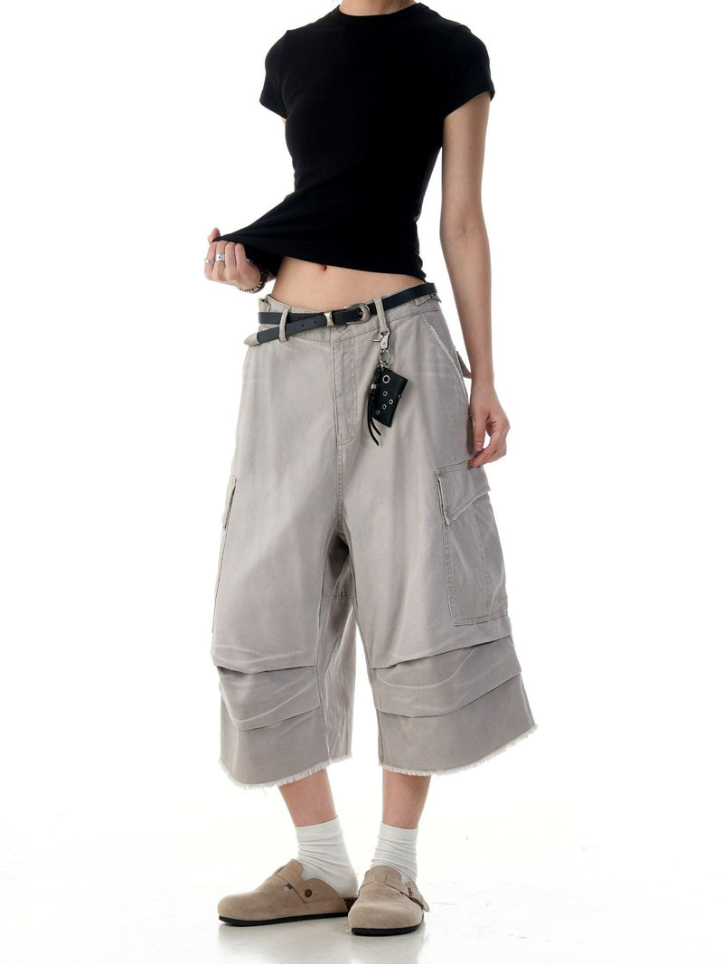 Beige cargo shorts on model, three-quarter front view with belt, hanging pouch, and wide legs