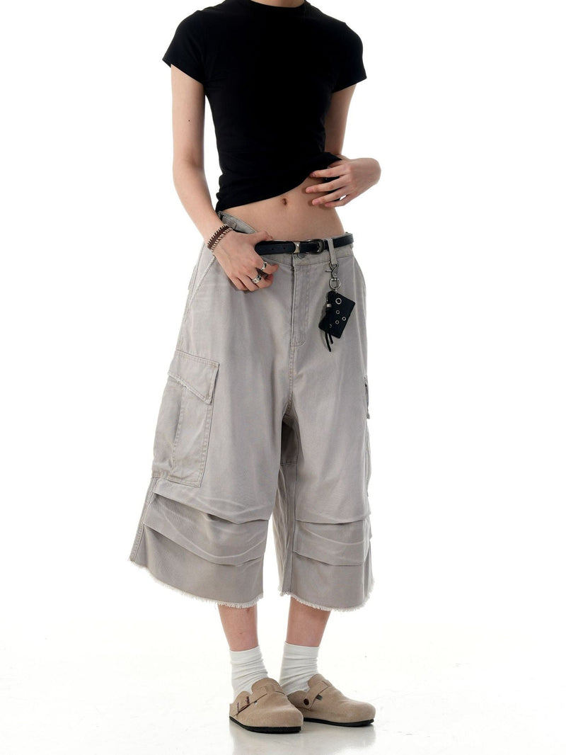 Beige cargo shorts on model, front view with side cargo pocket and frayed hem details