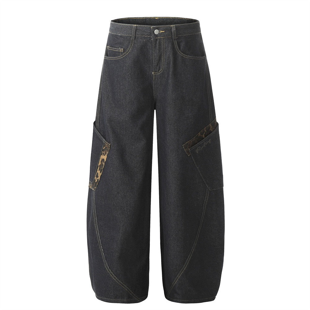 Dark raw denim wide-leg jeans with leopard camouflage patch accents and contrast gold stitching, front view
