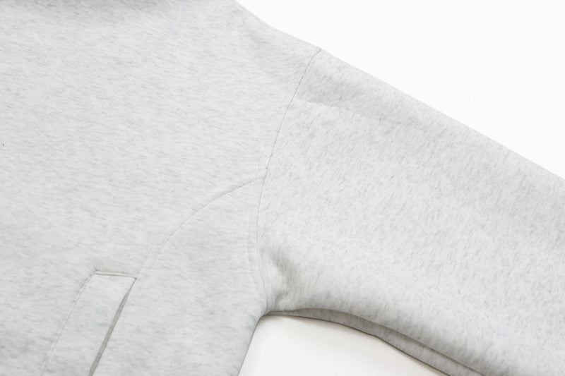 Ash grey hoodie sleeve and side seam close-up with kangaroo pocket edge