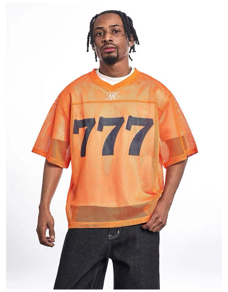 Orange mesh football jersey with oversized 777 graphic, short sleeves, and streetwear-inspired relaxed fit