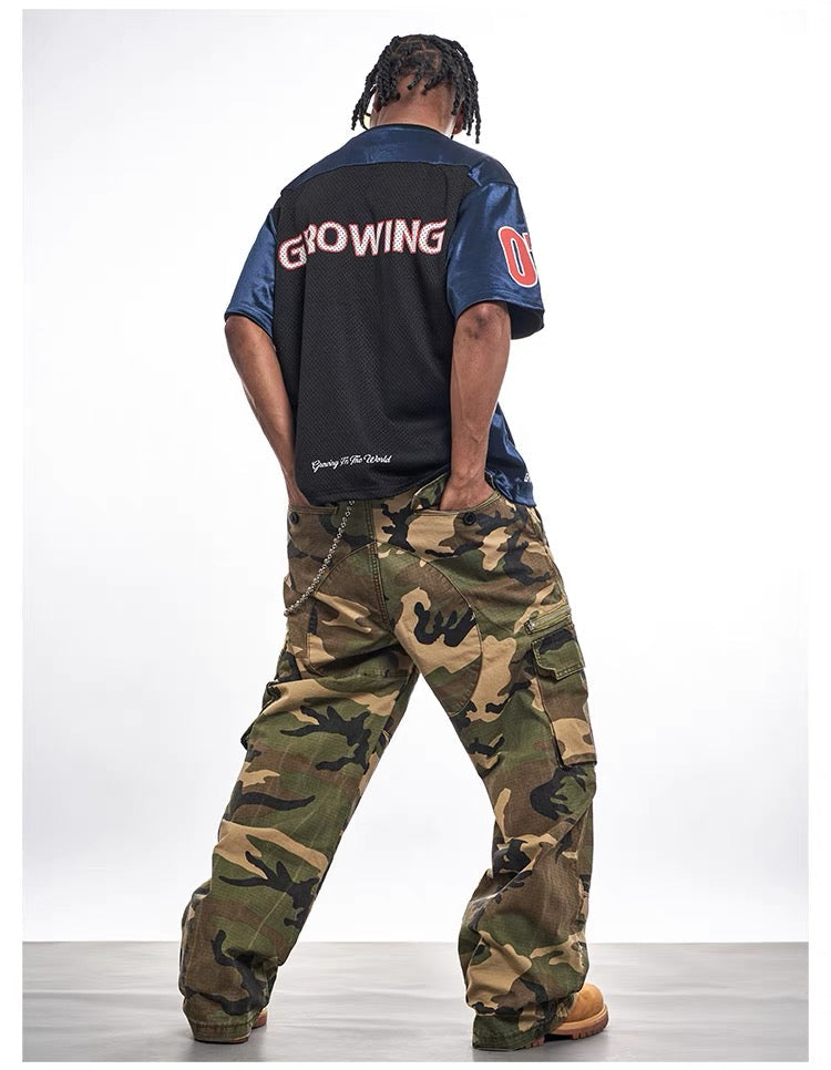 Oversized black and blue mesh varsity jersey tee with bold back lettering, styled with camo cargo pants