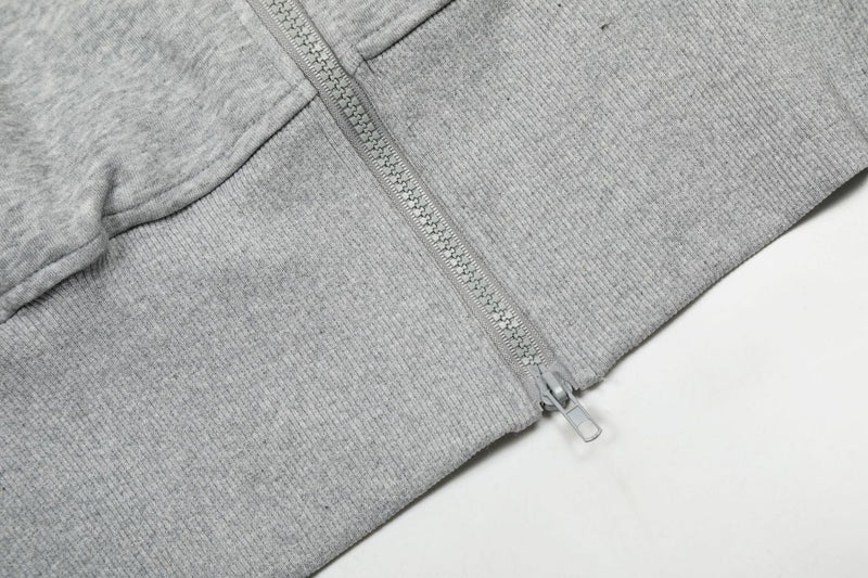 Close-up of gray hoodie zipper and ribbed hem at the lower front
