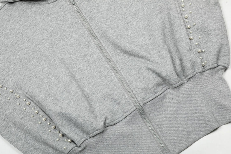 Close-up of gray cropped hoodie front with zipper, pearl-trimmed seam, and ribbed waistband