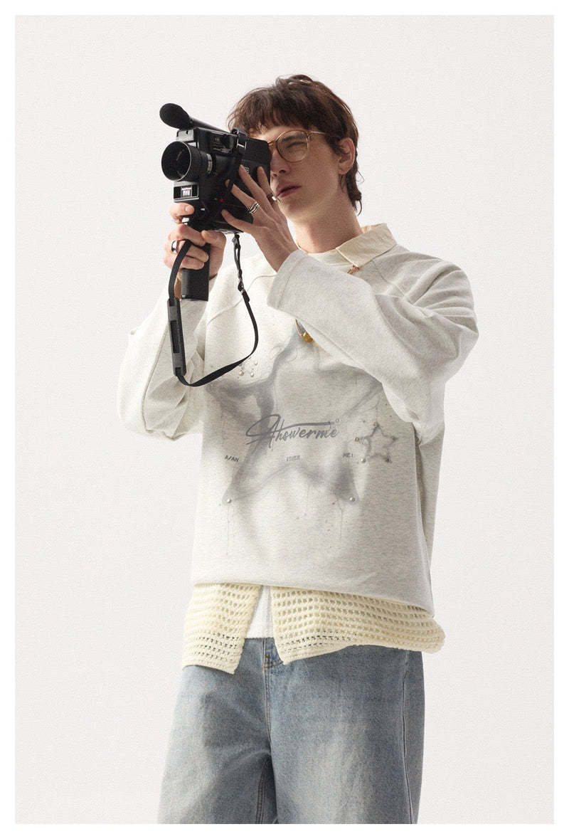 Model holding a camera while wearing the light gray star graphic long sleeve tee