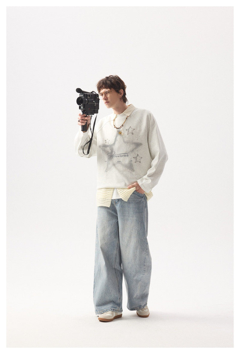 Model holding a camera in light gray star graphic long sleeve tee and wide-leg jeans
