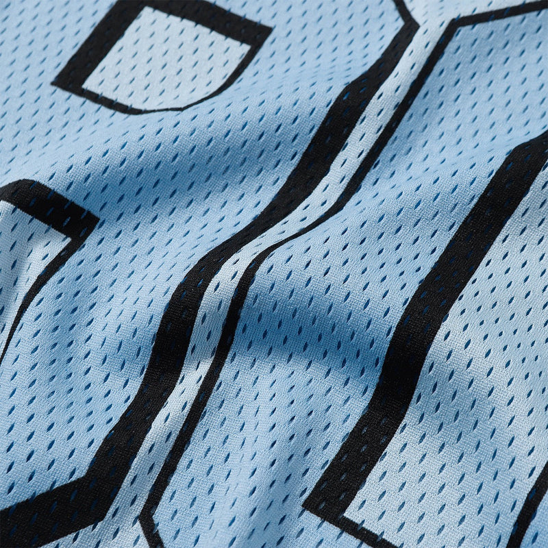 Close-up of a light blue mesh varsity jersey with bold black outlined lettering and perforated football shirt fabric