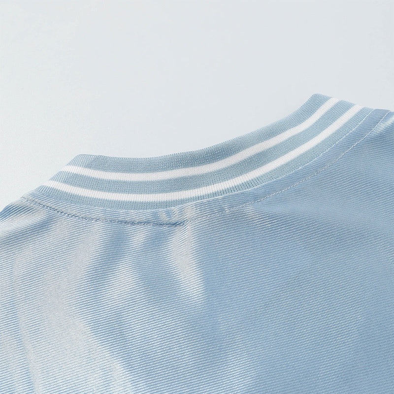 Close-up of a light blue mesh varsity jersey tee with white striped ribbed collar and stitched neckline