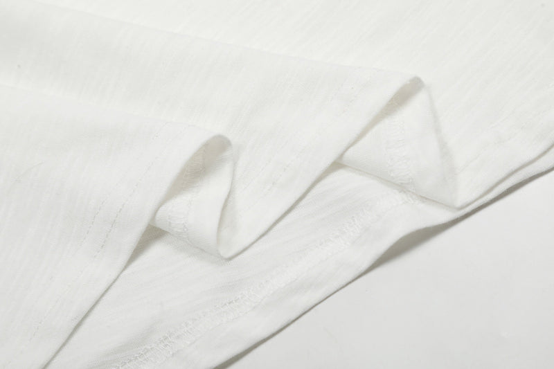 Close-up of white tee fabric showing smooth knit texture and seam stitching