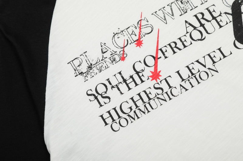 Close-up of front graphic on white raglan tee with black text and red star accents