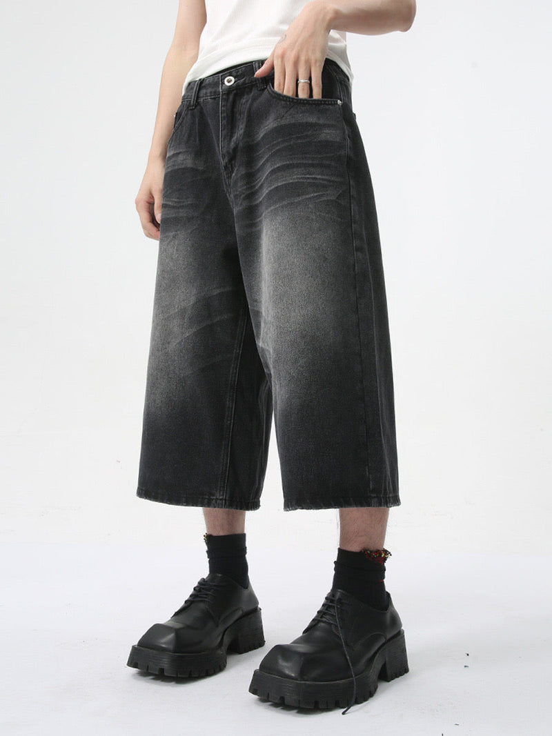 Side view of black wide-leg denim shorts showing a relaxed silhouette and soft fade