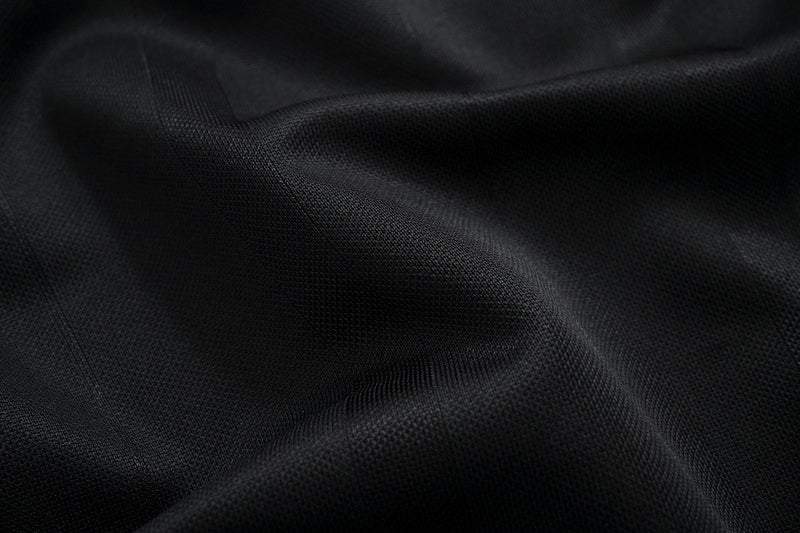 Close-up of black performance mesh fabric with a textured, breathable athletic tee surface and subtle triple-stripe design detailing
