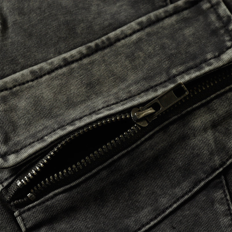 Close-up of a washed black tee pocket with exposed zipper and utility-style stitching details