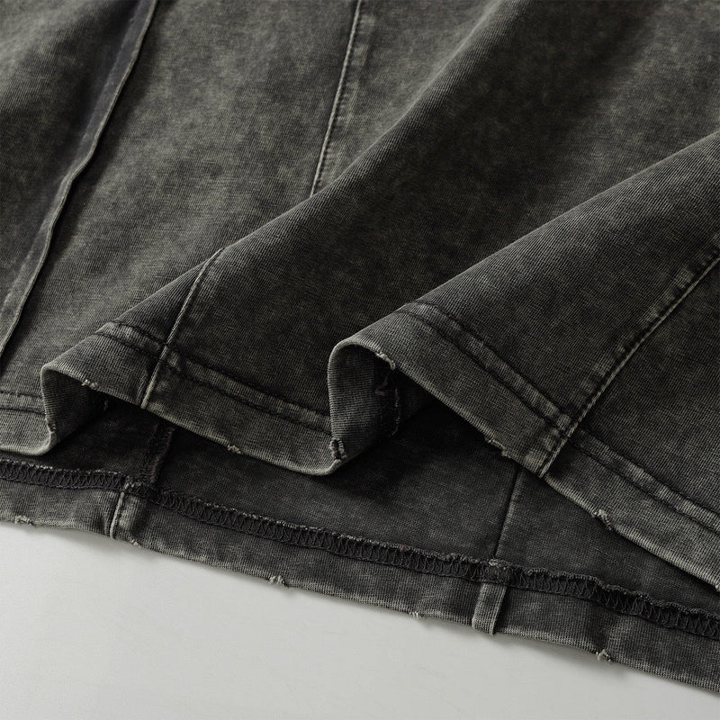 Washed black utility tee with raw hems and visible topstitching, showing layered fabric and relaxed sleeve cuffs