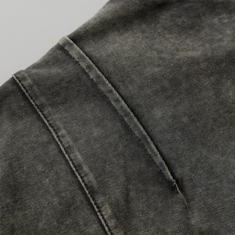 Close-up of a washed black tee with a dual zip chest pocket and rugged stitched seam detail