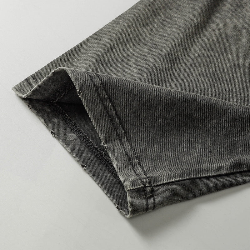 Close-up of a washed gray utility tee sleeve with raw seam detailing and worn hem stitching
