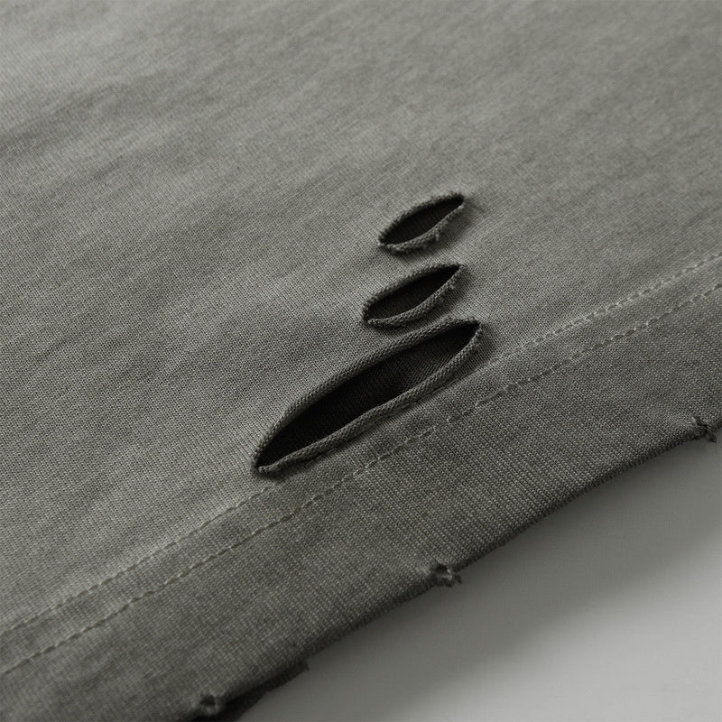Close-up of washed gray cotton tee hem with distressed panel slits and raw streetwear detailing
