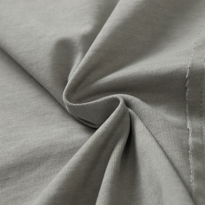 Close-up of a washed gray cotton tee with twisted fabric texture and distressed seam detail