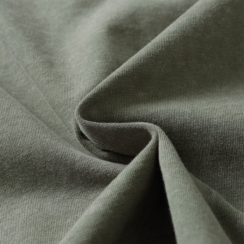 Close-up of olive washed cotton tee fabric with soft drape and vintage distressed texture