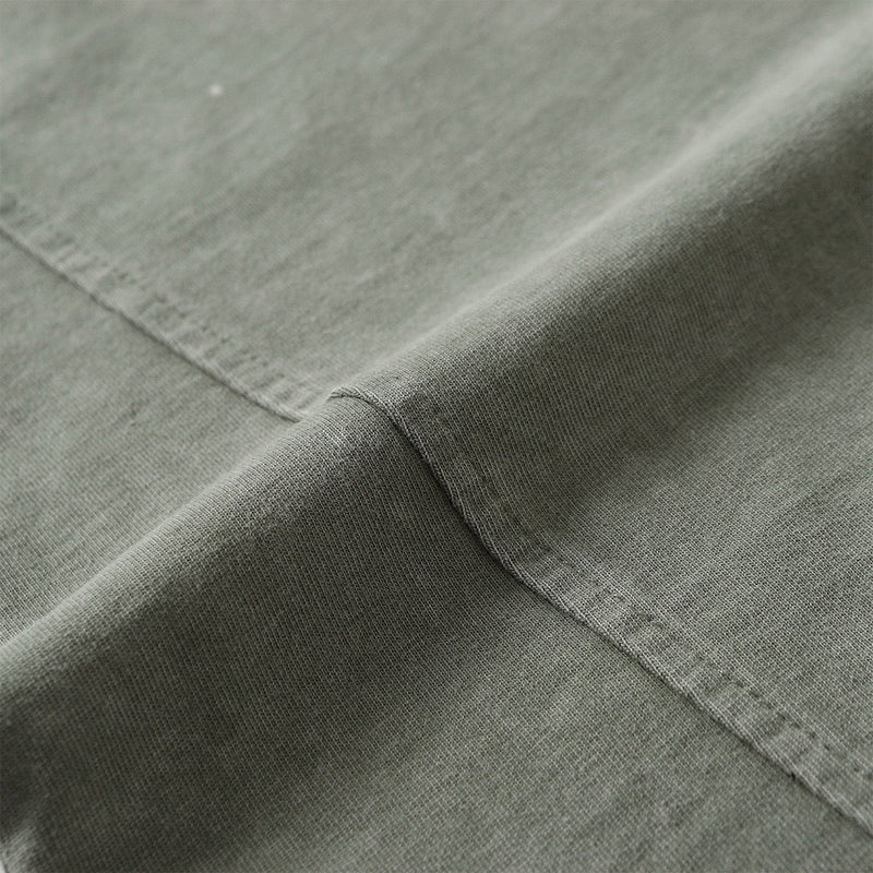 Close-up of olive washed panel tee fabric with distressed seams and vintage streetwear texture