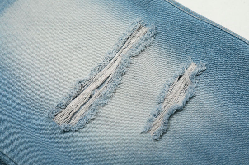 Close-up of two frayed ripped slits on light wash denim jorts