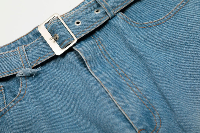 Close-up of silver buckle belt on light wash denim jorts