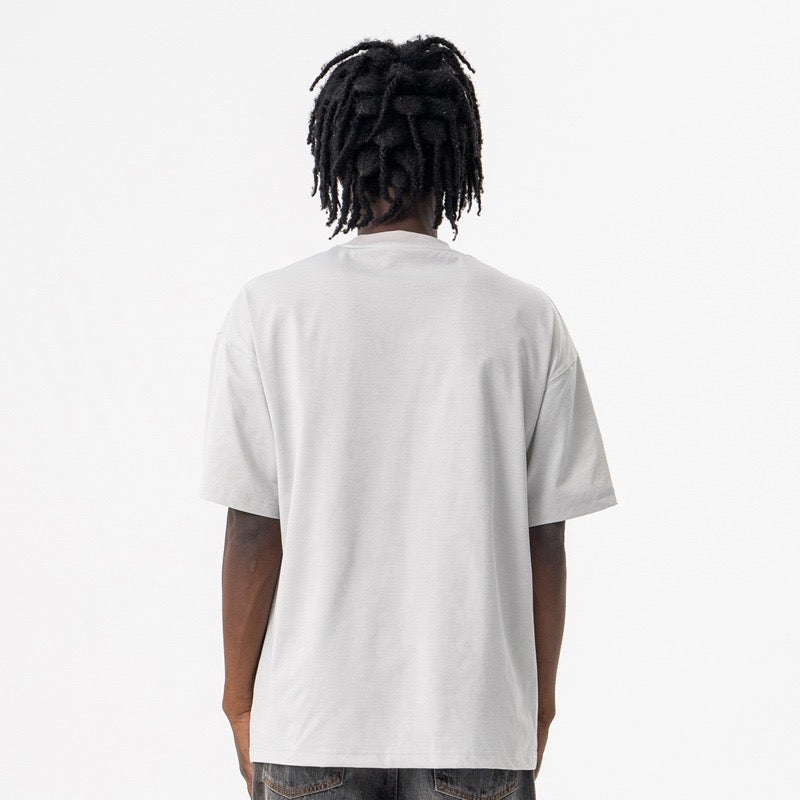 White oversized T-shirt with a loose fit, shown from the back on a model against a plain studio background