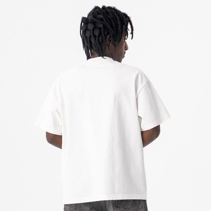 White oversized graphic tee worn by a model from the back, featuring a relaxed streetwear fit and crew neck detail