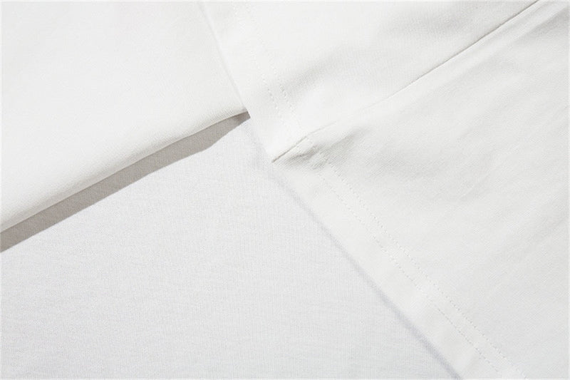 Close-up of a white graphic tee showing smooth fabric, neckline stitching, and subtle seam details