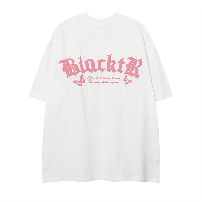 White oversized tee with pink gothic lettering and butterfly accents on the chest, featuring a dark romantic streetwear graphic