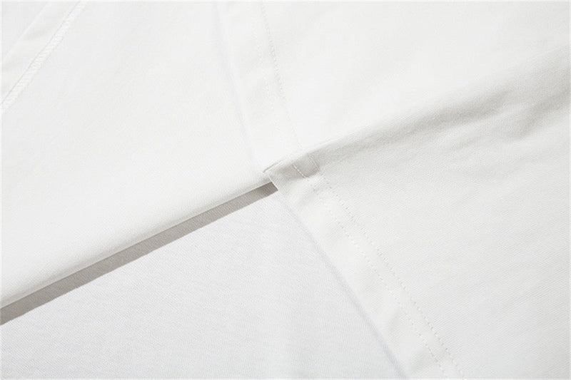 Close-up of a white oversized tee showing soft fabric, sleeve seam, and clean minimalist streetwear styling