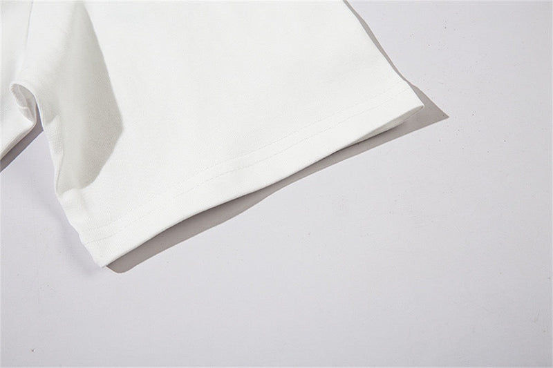 Close-up of a white oversized graphic tee sleeve with stitched hem and soft cotton texture on a clean background