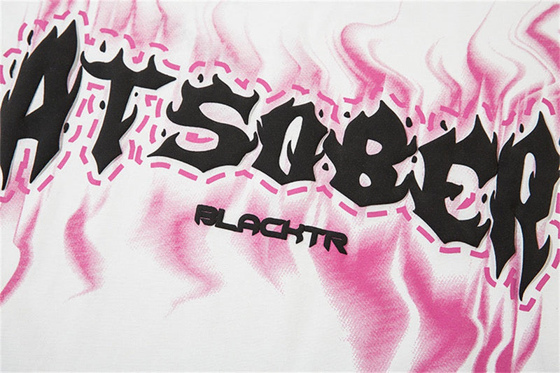 Close-up of a white oversized tee with pink flame graphics and bold black ATSOBER logo text across the chest