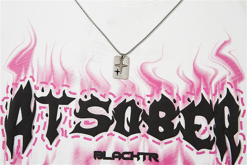 White oversized tee with pink flame graphics and bold black ATSOBER lettering, plus a silver star pendant necklace detail
