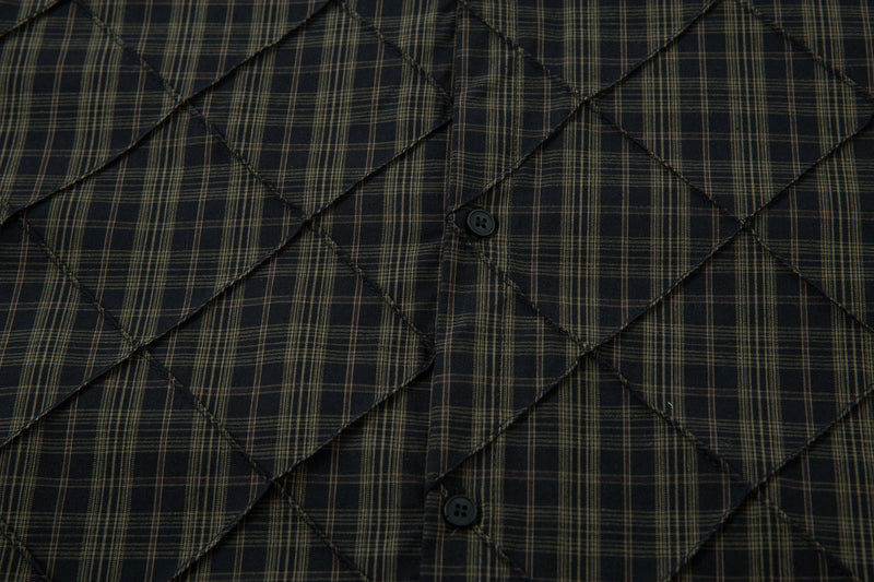 Close-up of black plaid quilted shirt front showing button placket and diamond stitching