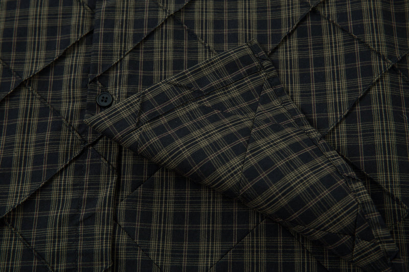 Close-up of plaid quilted shirt sleeve and front panel with black button detail