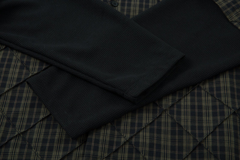 Close-up of black ribbed long sleeve layered under plaid quilted shirt