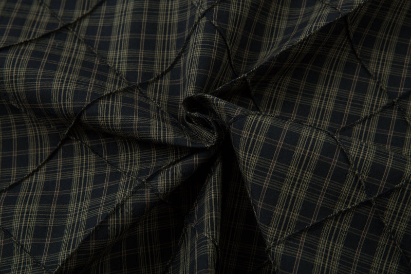 Close-up of gathered black plaid quilted fabric with diagonal stitching