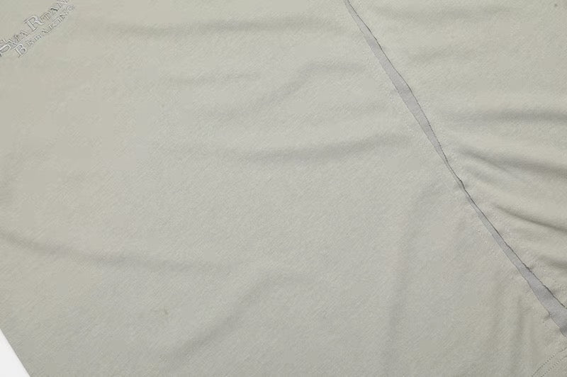 Close-up of a cream cotton tee with asymmetric seam stitching and subtle deconstructed texture
