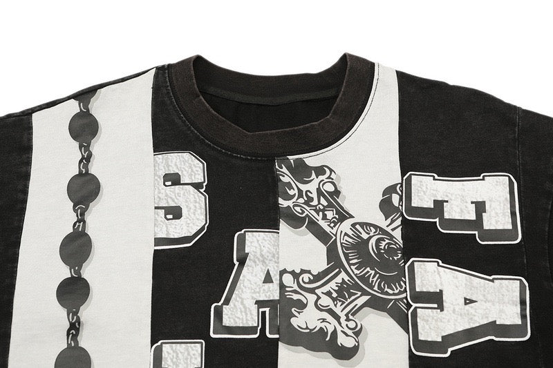 Black cropped boxy tee with white cross panel graphics, gothic lettering, and chain detail across the chest