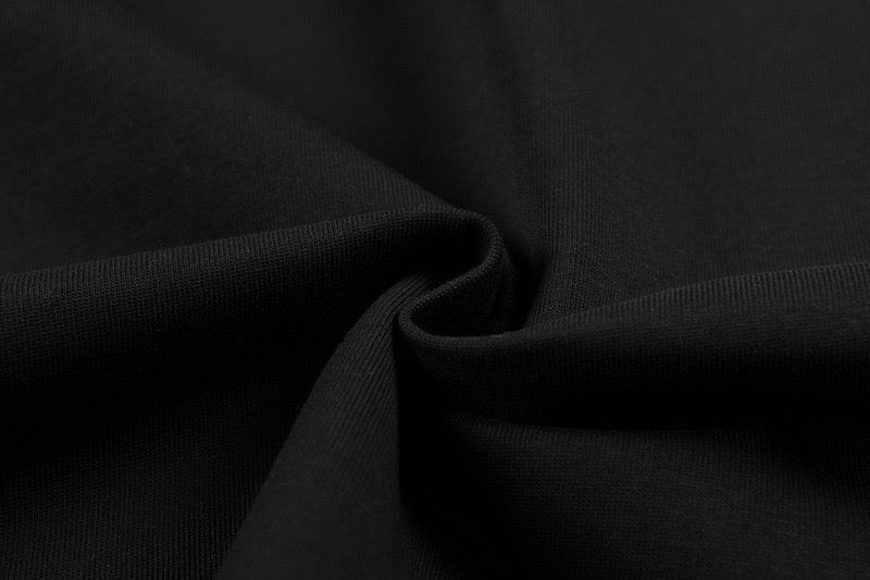 Black oversized graphic tee fabric close-up with textured knit and draped folds
